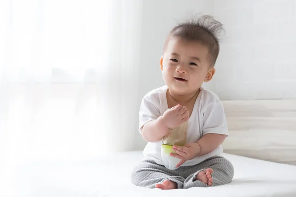 Anak Asia Memegang Susu Botol Dan Duduk Tempat Tidur Putih — Stok Foto
