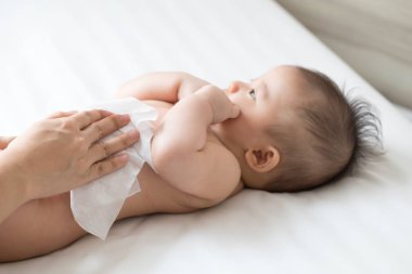 Anne altını değiştirirken, altını ıslak mendille temizler, altını değiştirirken, ellerini, yüzünü ya da bacağını silerken, ıslak mendil kavramlı anne ve bebek için kişisel hijyen.