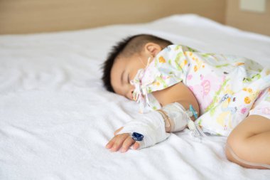 Asian baby boy sleeping on bed with infusion set at child department in the hospital. Children with infectious diseases IPD, Invasive Pneumococcal Disease concept. Infant model one year six months clipart