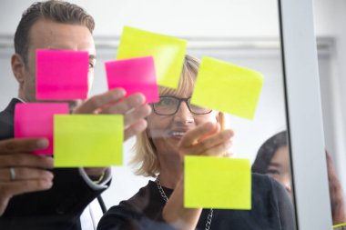 Kanban tahtasında görevlerini takip ediyor. Çevik geliştirme metodolojisi görev denetimini kullanarak. Ofiste Scrum Görev panosuna yapışkan not ekleyerek takım üyeleri