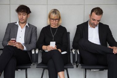 İnsanlar bir iş görüşmesi için bekliyor oturan ve cep telefonu sosyal medya uygulaması kullanarak. İnsan kaynakları işe alım konsepti