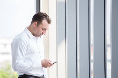 İş adamı özel metin yazarak cep telefonu uygulaması kullanarak. Ofis bina içinde iş iş için akıllı tutmak genç Kafkas adam