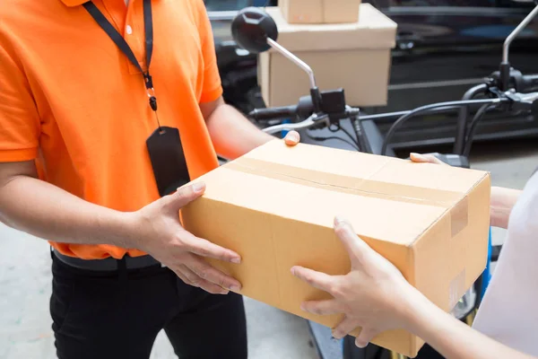Женская рука принимает доставку коробок от курьера, доставляет товары на мотоцикле, быстрый и бесплатный транспорт — стоковое фото