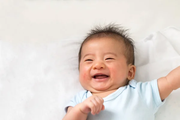 Bayi Asia kecil yang bahagia tersenyum sambil berbaring di tempat tidur putih — Stok Foto