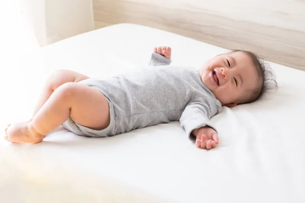 Anak laki-laki Asia tersenyum dan bersantai di kamar tidur putih — Stok Foto
