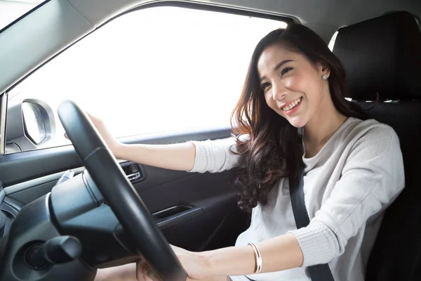Mujer asiática joven conduciendo su coche y abrocharse el cinturón de seguridad con expresión positiva alegre durante el viaje de viaje, sonrisa relajada mujer feliz en concepto de vacaciones viaje por carretera — Foto de Stock