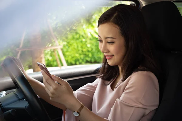 Mujer asiática usando el teléfono y enviando un mensaje al volante, Mujer conduciendo un coche con el uso de navegación o aplicación en el teléfono inteligente, GPS Tecnología inteligente y concepto de redes sociales —  Fotos de Stock