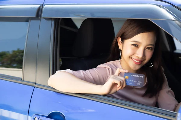 Heureuse jeune femme asiatique tenant une carte de paiement ou une carte de crédit et servant à payer l'essence, le diesel et d'autres carburants dans les stations-service, Chauffeur avec des cartes de flotte pour ravitailler la voiture — Photo