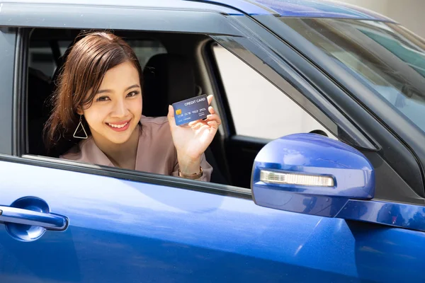 Feliz jovem asiática segurando cartão de pagamento ou cartão de crédito e usado para pagar a gasolina, diesel e outros combustíveis em postos de gasolina, motorista com cartões de frota para reabastecer carro — Fotografia de Stock