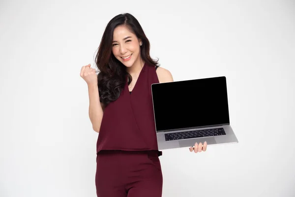 Porträtt av en upphetsad asiatisk kvinna som innehar bärbar dator och firar framgång över vit bakgrund, höja armarna med en blick av lycka, kvinnlig modell — Stockfoto