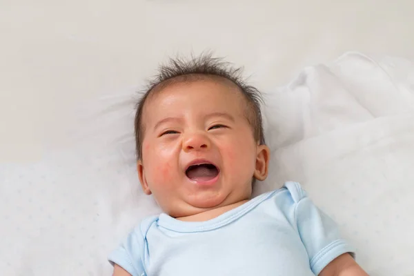 Bayi Asia kecil yang bahagia tersenyum sambil berbaring di tempat tidur putih — Stok Foto