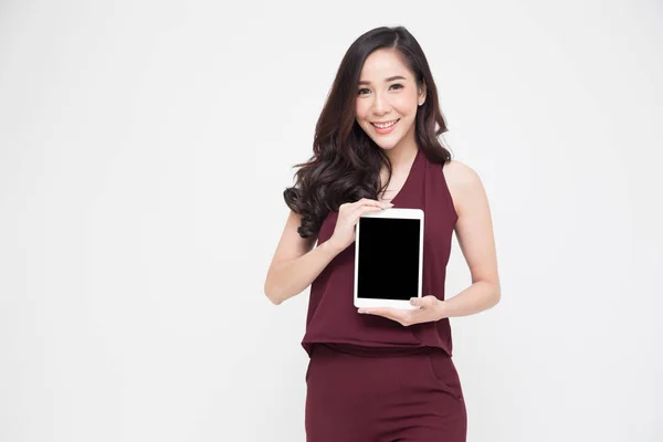 Porträtt av en glad vacker flicka iklädd röd klänning och visar eller presentera tablet-programmet isolerade över vit bakgrund, asiatiska thailändska modellen — Stockfoto