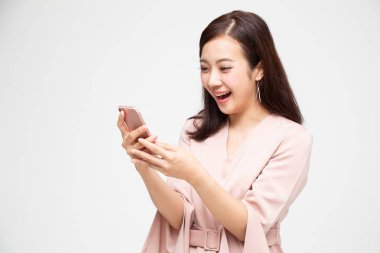 Neşeli genç Asyalı kadın akıllı telefon kullanarak ve iyi haber alma