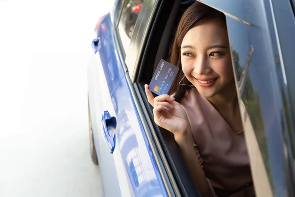 Glad ung asiatisk kvinna håller betalkort eller kreditkort och används för att betala för bensin, diesel och andra bränslen vid bensinstationer, Driver med flottan kort för att tanka bilen — Stockfoto