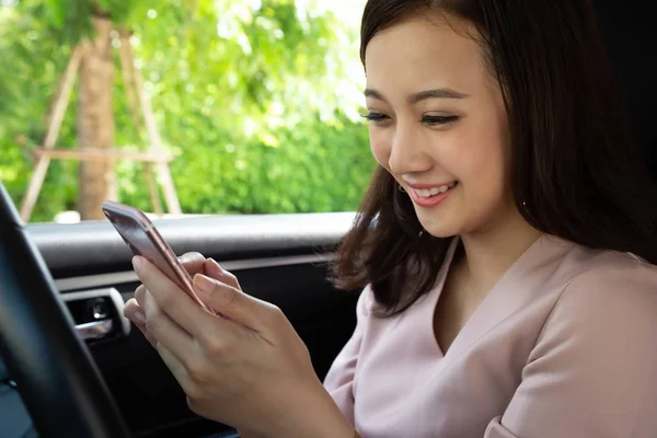 Mujer asiática usando teléfono móvil y disfrutar de mensajes con grupo de amigos después de viajar en las últimas vacaciones en su coche —  Fotos de Stock