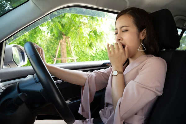 Asiática mujer trabajadora sentada en coche y bostezando mientras conduce en su coche — Foto de Stock