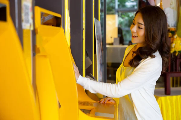 Mujer asiática joven retirando dinero con una tarjeta en la máquina automática, Mujer de pie en el cajero automático del banco — Foto de Stock
