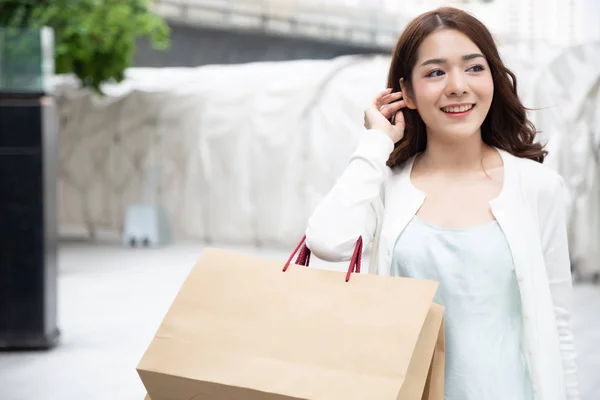 Heureuse belle femme asiatique appréciant excité et tenant des sacs à provisions marron — Photo