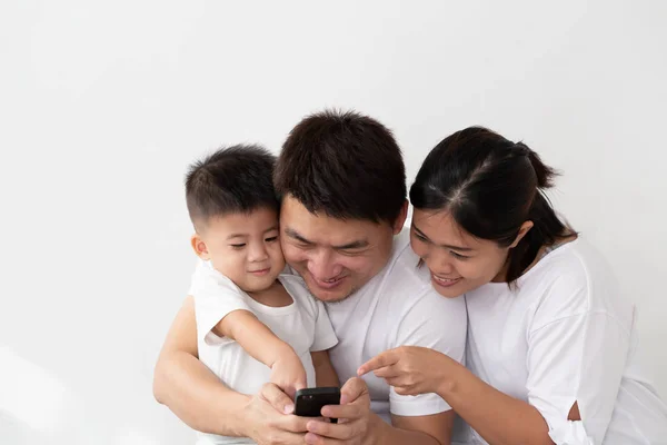 Весела молода Азіатська сім'я з сином сміючись дивляться смішне відео на смартфоні — стокове фото