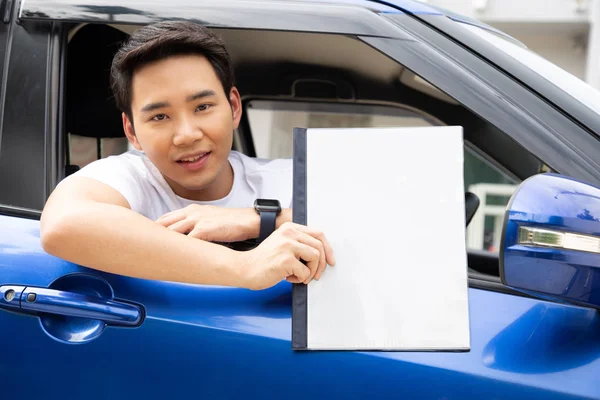 Молодой азиат держит книгу правил и сидит в машине , — стоковое фото
