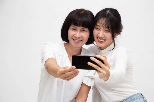 Feliz asiático senior mujer y hija tomando selfie juntos aislado en blanco fondo —  Fotos de Stock