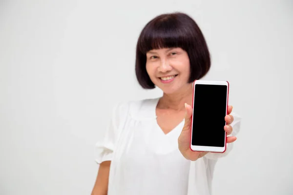 Retrato de wowan sênior asiático mostrando ou apresentando aplicativo de telefone celular na mão isolado sobre fundo branco — Fotografia de Stock