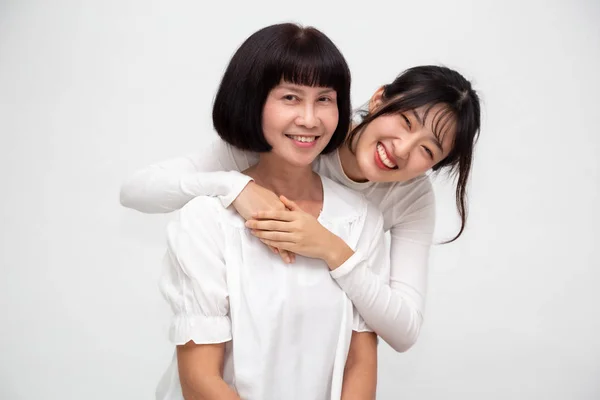 Щасливі люблячі літні зрілі азіатські мати і дочка сміятися і обійматися, посміхаючись молода жінка охоплює старших середнього віку мама веселяться разом ізольовані на білому фоні — стокове фото