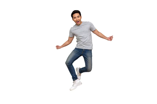 Opgewonden aziatische jongeman in grijs t-shirt springen terwijl vieren succes geïsoleerd over witte achtergrond, volledige lengte portret concept — Stockfoto