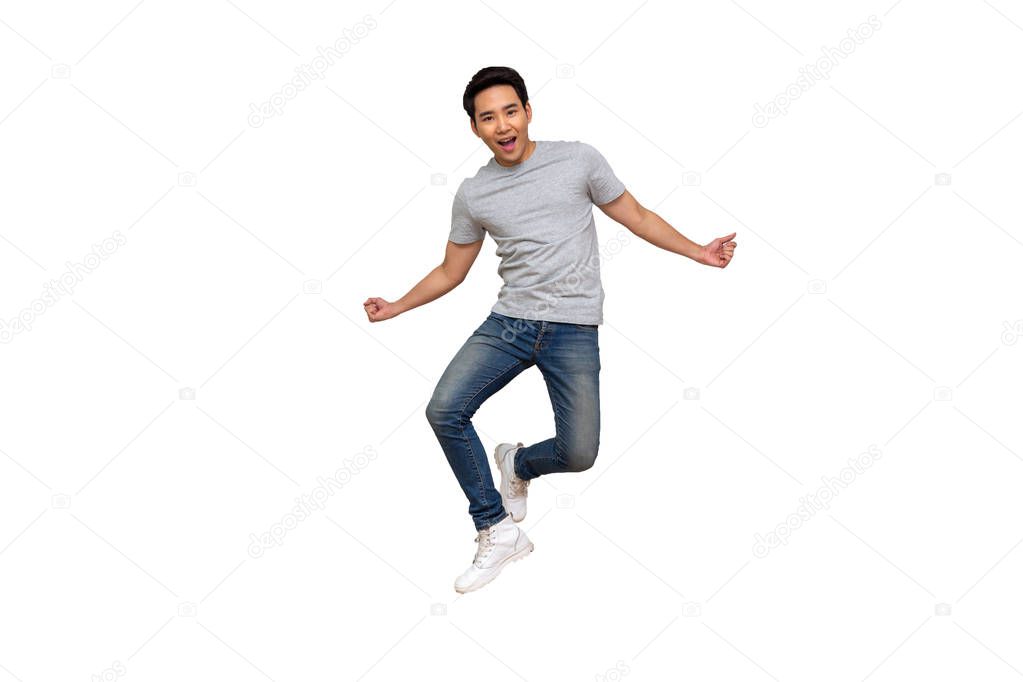 Excited Asian young man in gray t-shirt jumping while celebrating success isolated over white background, Full length portrait concept
