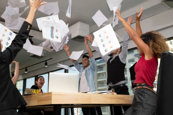 Grupo de equipe de negócios jogando documentos e triunfar com armas para cima enquanto celebra o sucesso no escritório de co-trabalho de inicialização — Fotografia de Stock