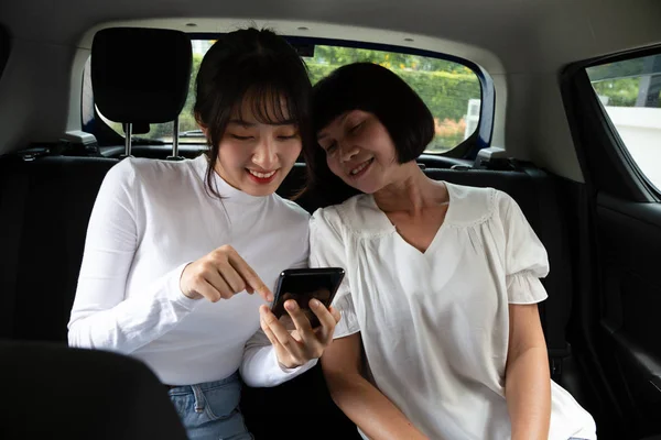 Joyeux asiatique mère et fille assis dans la voiture et toucher téléphone mobile — Photo