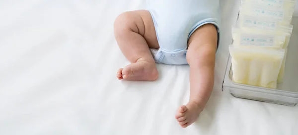 Нога новорожденного ребенка и грудное молоко заморожены в пластиковом пакете хранения, грудное вскармливание от сцеживания матери молока — стоковое фото
