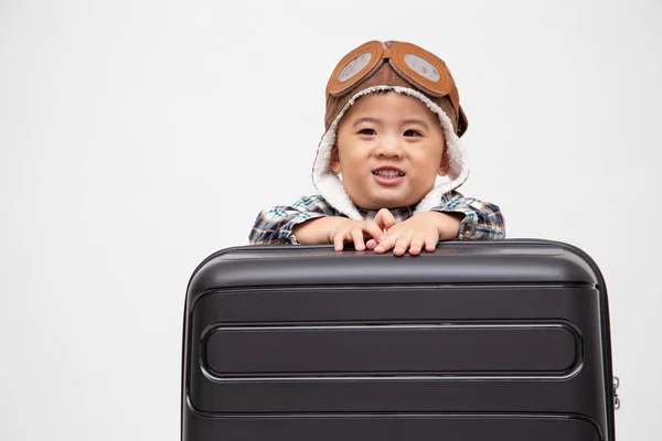 Happy kid Asian boy sitting behind black suitcase isolated over white background, Dreams of travel concept, Two year one month old