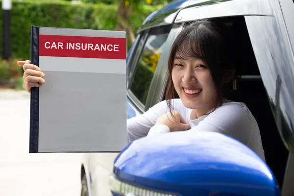 Happy Asian woman holding car insurance document book and sitting in car, Safety vehicle and protection client person concept — Stock Photo, Image
