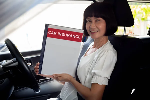 Happy Asian senior woman holding car insurance document book and sitting in car, Safety vehicle and protection client person concept — Stock Photo, Image