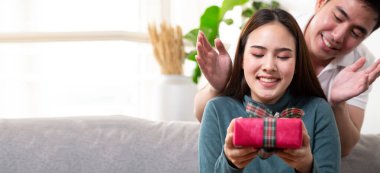 Sürpriz yapmayı seven mutlu Asyalı çift ellerinde kırmızı hediye kutusu, erkek arkadaş ve kız arkadaş kavramı