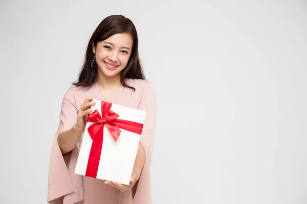 Beyaz arka planda saklanmış hediye kutusuyla mutlu Asyalı kadın gülüşü. Aşık ergen kızlar, sevgililerinden hediyeler alıyorlar. Yeni Yıl, Noel ve Sevgililer Günü konsepti — Stok fotoğraf