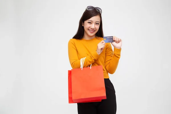 Retrato de una joven feliz sosteniendo bolsas de compras y tarjeta de crédito aislada sobre fondo blanco, venta de fin de año o mediados de año de liquidación de promoción de venta para el concepto Shopaholic, modelo femenino asiático —  Fotos de Stock