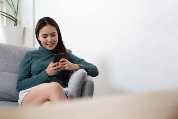 Asiático jóvenes mujeres charlando por teléfono móvil en el sofá en casa , —  Fotos de Stock
