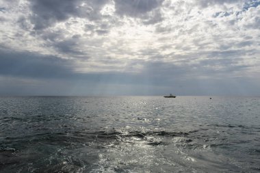 Bulutlu yağmurlu gökyüzü, Güneş ışınları deniz yüzeyine parlayan üzerinde