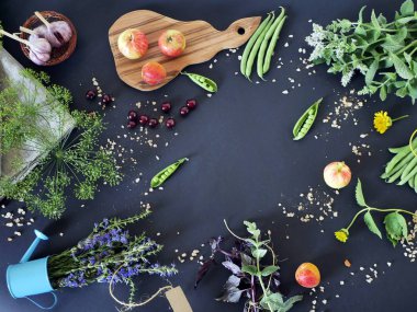 Üst görünüm, karanlık bir arka planda deniz tuzu, çiçekler, yeşillikler, baharatlar ve meyveler, yaz bir kompozisyon