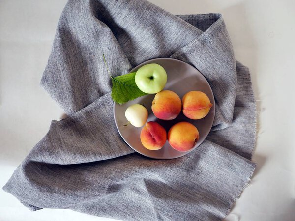 Концепция лета, осени, урожая, здоровья. Декоративная композиция, натюрморт персиков, яблок, листья на светлом фоне, вид сверху
