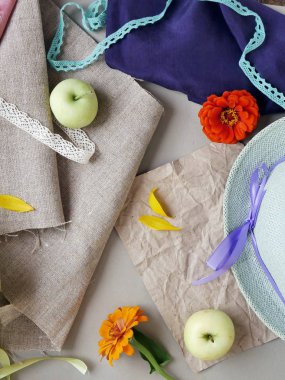 Elma, sarı yaprakları, yeşil şapka ve hafif bir arka plan gri tuval ve pembe ve mor bez, taze çiçekler görünümü top. Mevsimlik dekoratif kompozisyon, natürmort. Yaz, sonbahar