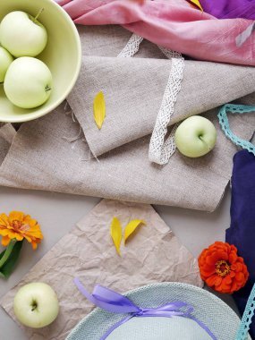 Elma, sarı yaprakları, yeşil şapka ve hafif bir arka plan gri tuval ve pembe ve mor bez, taze çiçekler görünümü top. Mevsimlik dekoratif kompozisyon, natürmort. Yaz, sonbahar