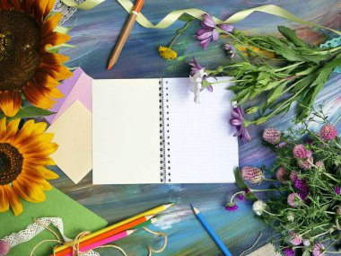 Sanat malzemeleri, Not defteri ve kireçli bir mavi arka plan, sonbahar ve okul, üstten görünüm kavramı üzerinde çiçekler parlak dekoratif bileşimi