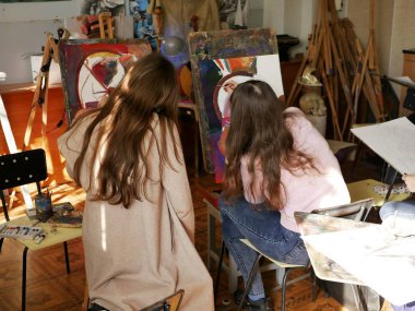 İki genç kız Sanat Okulu, iç sanat atölyesi, Avrupa görünüm, arkadaki, güneşli atölye, eğitim uzun saçlı gençler boyamak öğrenme
