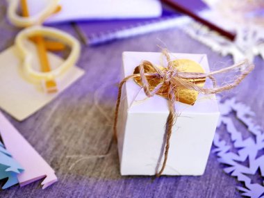 El yapımı bir dekor, boş bir defter masada kış tatil, yılbaşı, Sevgililer günü, atmosfer romantik bir tebrik için arka plan ışık Mevsimlik arka plan üzerinde altın bir kalbi olan beyaz hediye kutusu