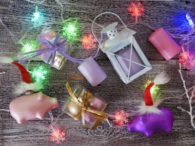   Noel oyuncak domuz yavruları Noel Baba'nın kırmızı şapka, Festival aydınlatma, mumlar, kutuları topları ile dekoratif mevsimlik bileşimi, fener bir ahşap masa, pembe rengi, domuz, Noel, üst yılı görüntüleyin.