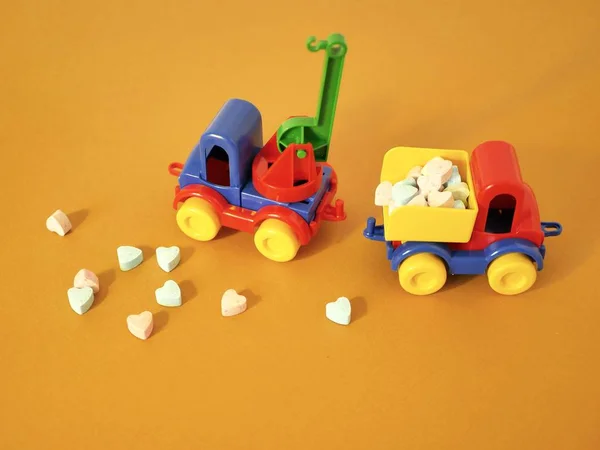 Arkadaki iki oyuncak arabalar bir bileşimi vitamin tabletleri kalp şeklinde, tatlı tablet parlak bir arka plan, aşk, sağlık, Valentin ile kutlama için kart kavramı üzerinde dağınık