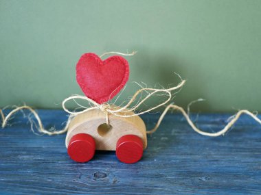 Dekoratif bileşimi bir oyuncak araba ve bir kalp keçe mavi arka plan, Sevgililer günü, tatil dekorasyon, tebrik kartı için tebrikler kavramı üzerinde yapılmış